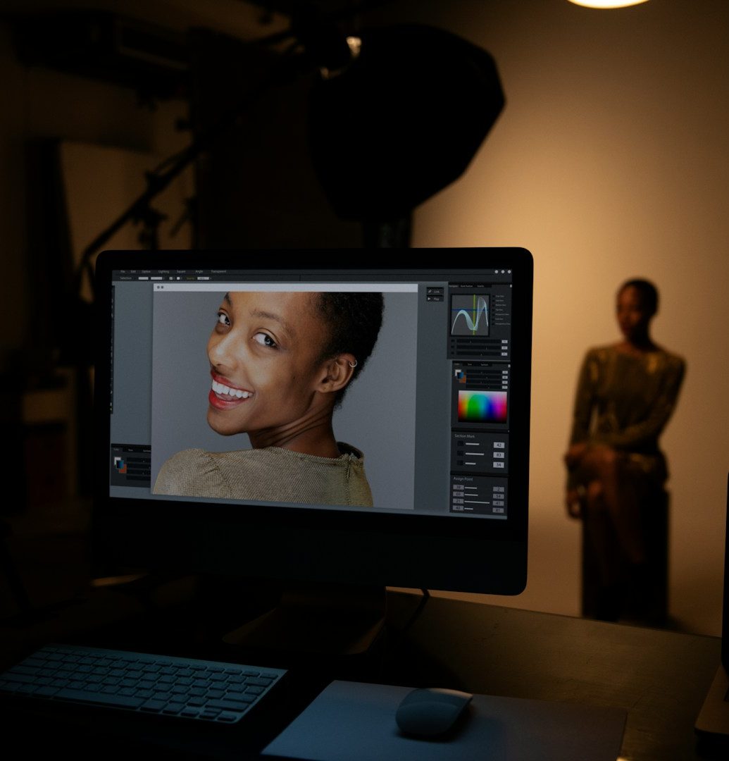 Donna con un sorriso luminoso in uno studio, seduta con lo schermo di un computer che mostra il suo ritratto.